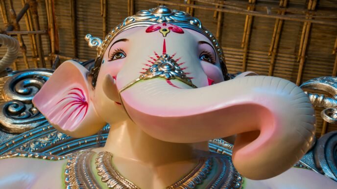 woman in gold and red sari dress holding pink elephant figurine